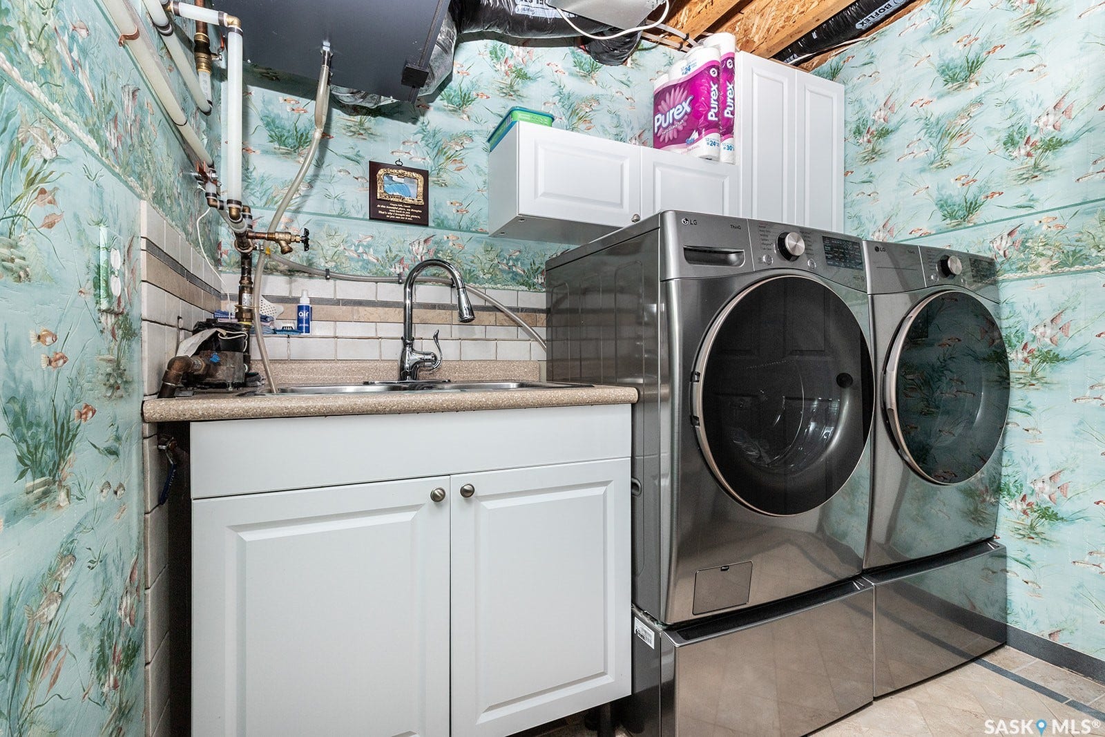 Laundry area with white cabinetry with a utility sink