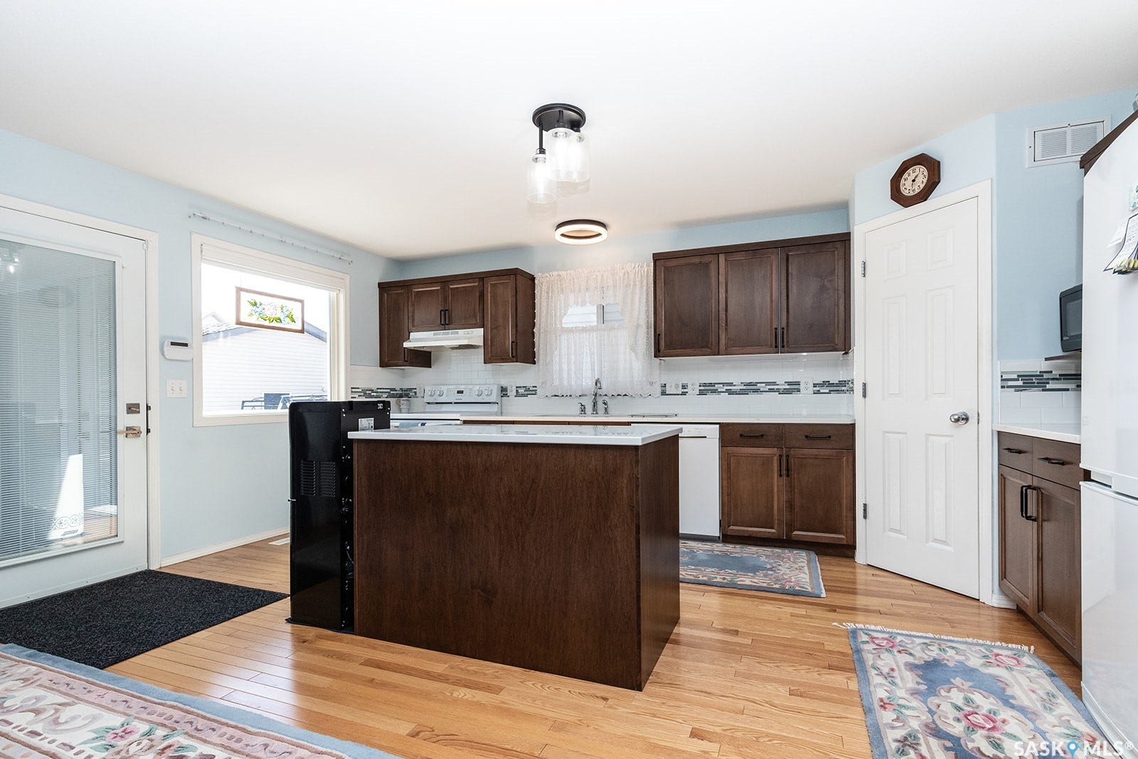 Kitchen featuring hardwood flooring, dark wood cabinetry, a central island with quartz countertop, and a glass-paned exterior door