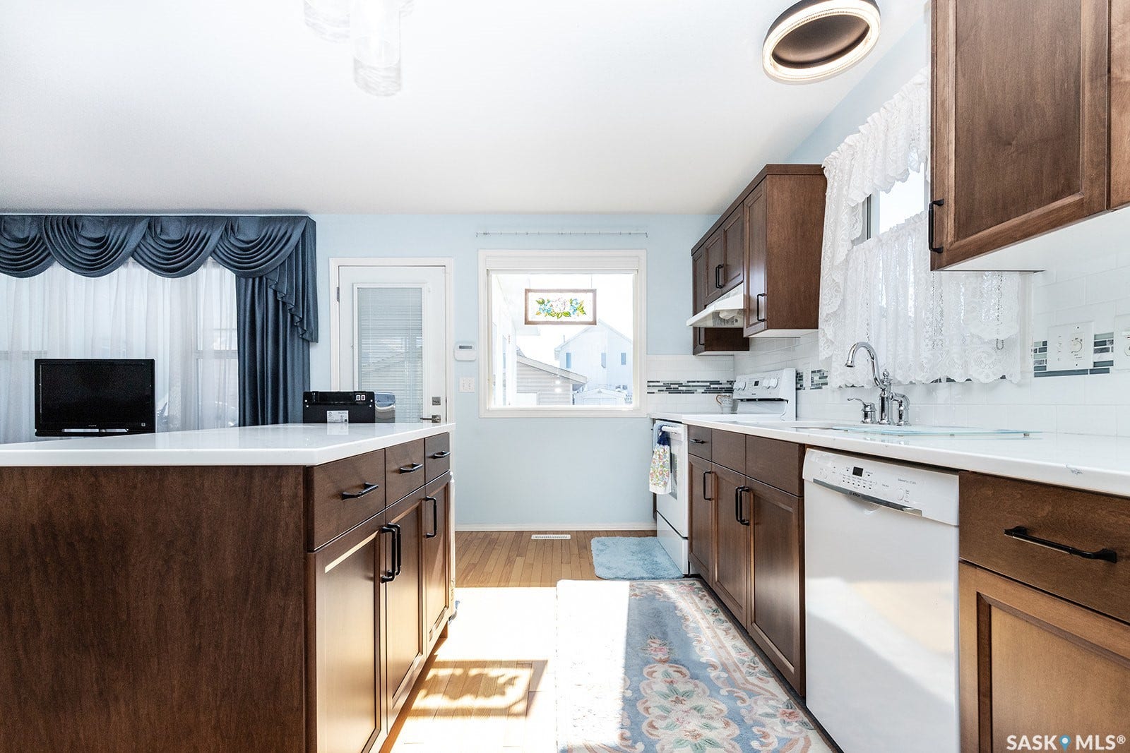 Kitchen featuring hardwood flooring, dark wood cabinetry, a central island with a light-toned quartz countertop