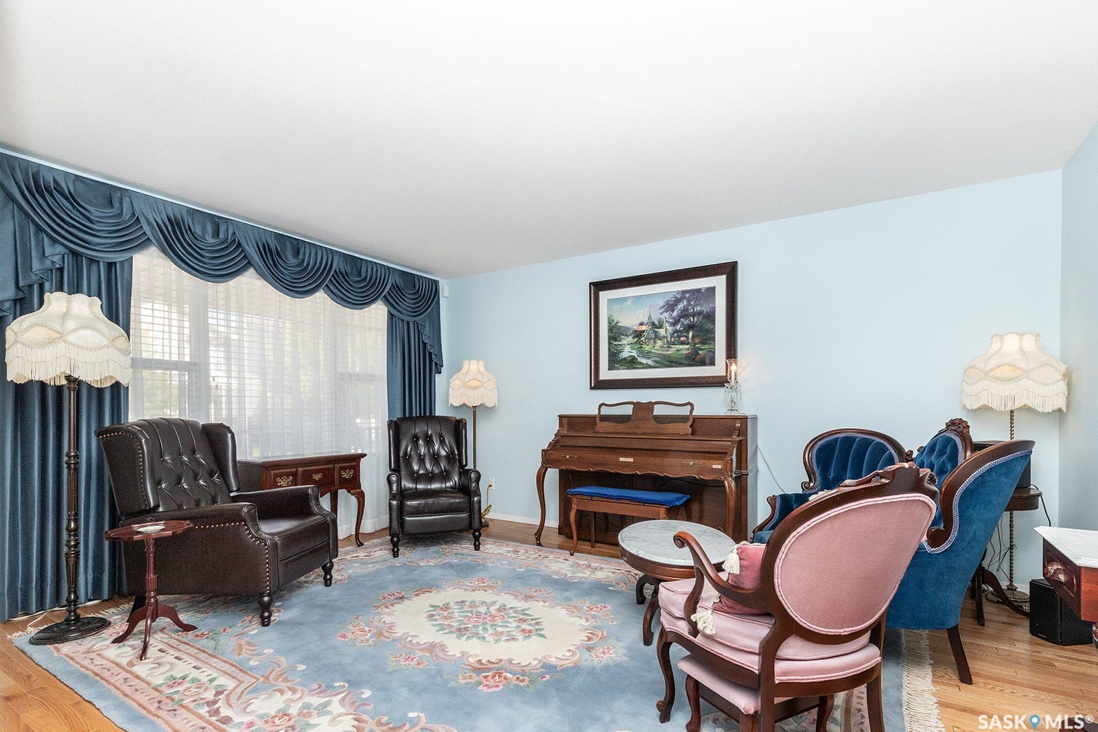 Featuring hardwood flooring and a large window with valance and drapes