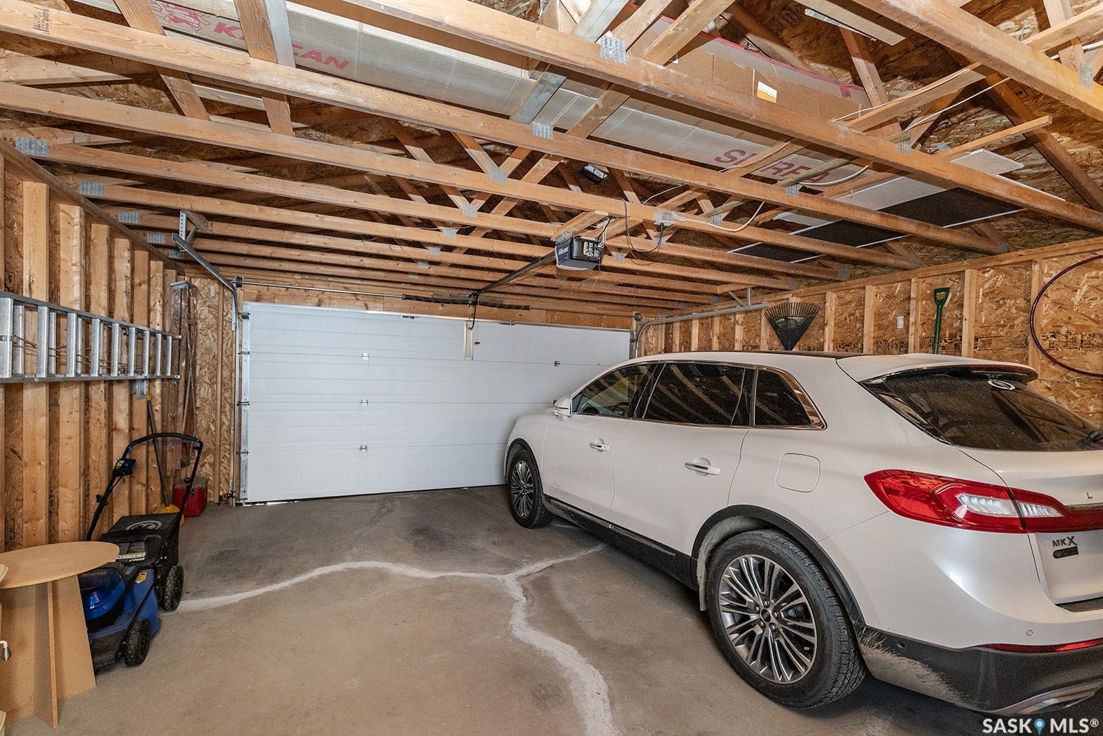 Detached double garage featuring an automatic overhead door and exposed wood beam ceiling
