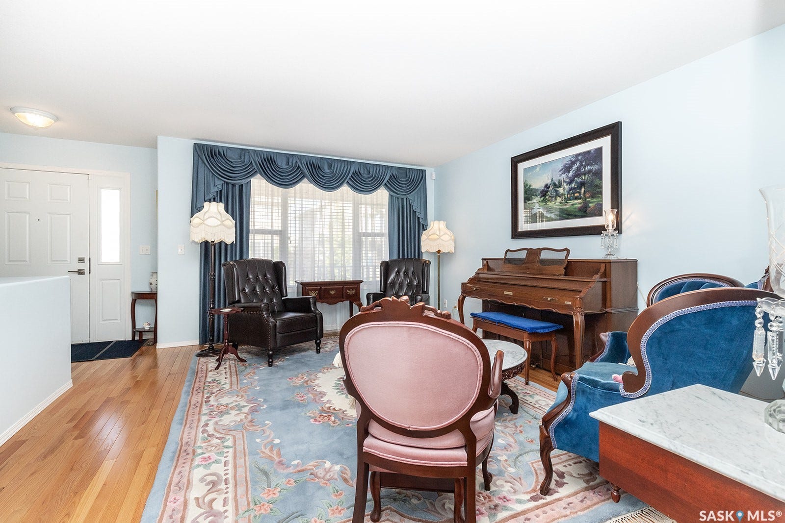 Featuring hardwood flooring and a large window with valance and drapes