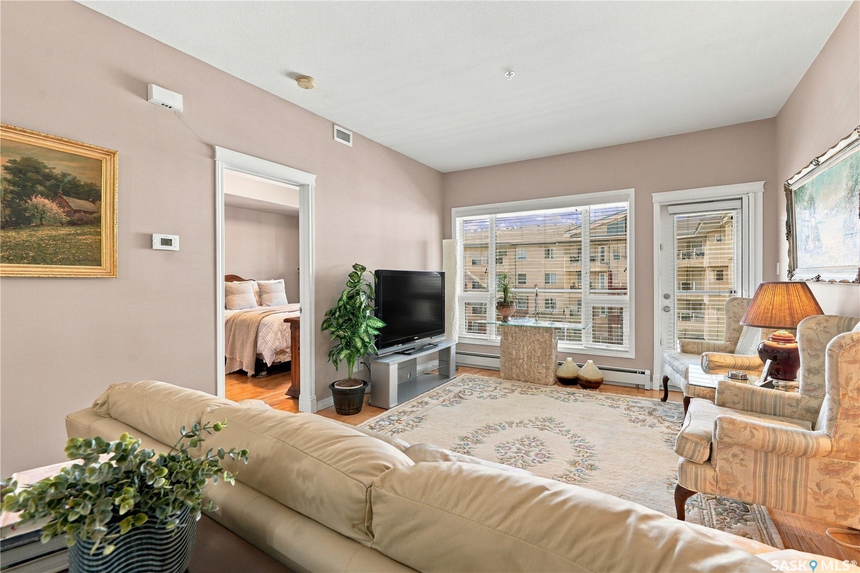 Light-colored walls in a neutral tone, hardwood flooring, and a large window with white trim