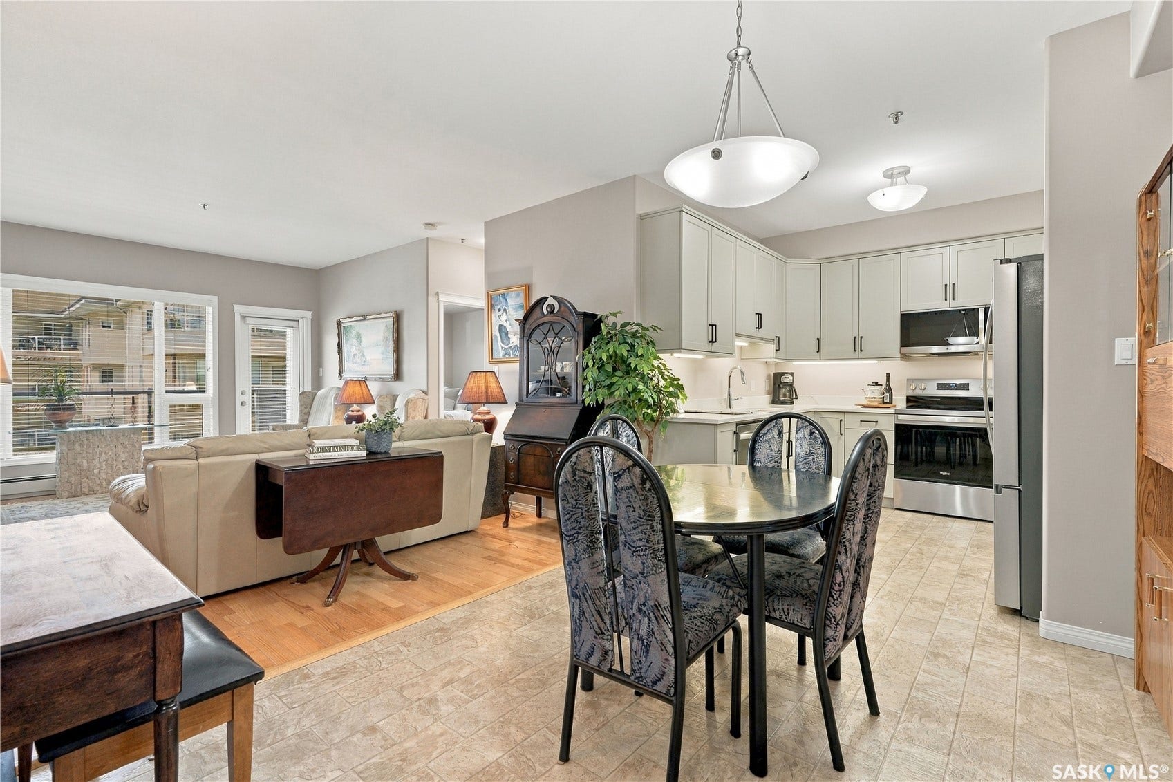 Open-concept living space featuring wood-finish flooring, a kitchen with light-toned cabinetry and stainless steel appliances, and a dining area with tiled flooring