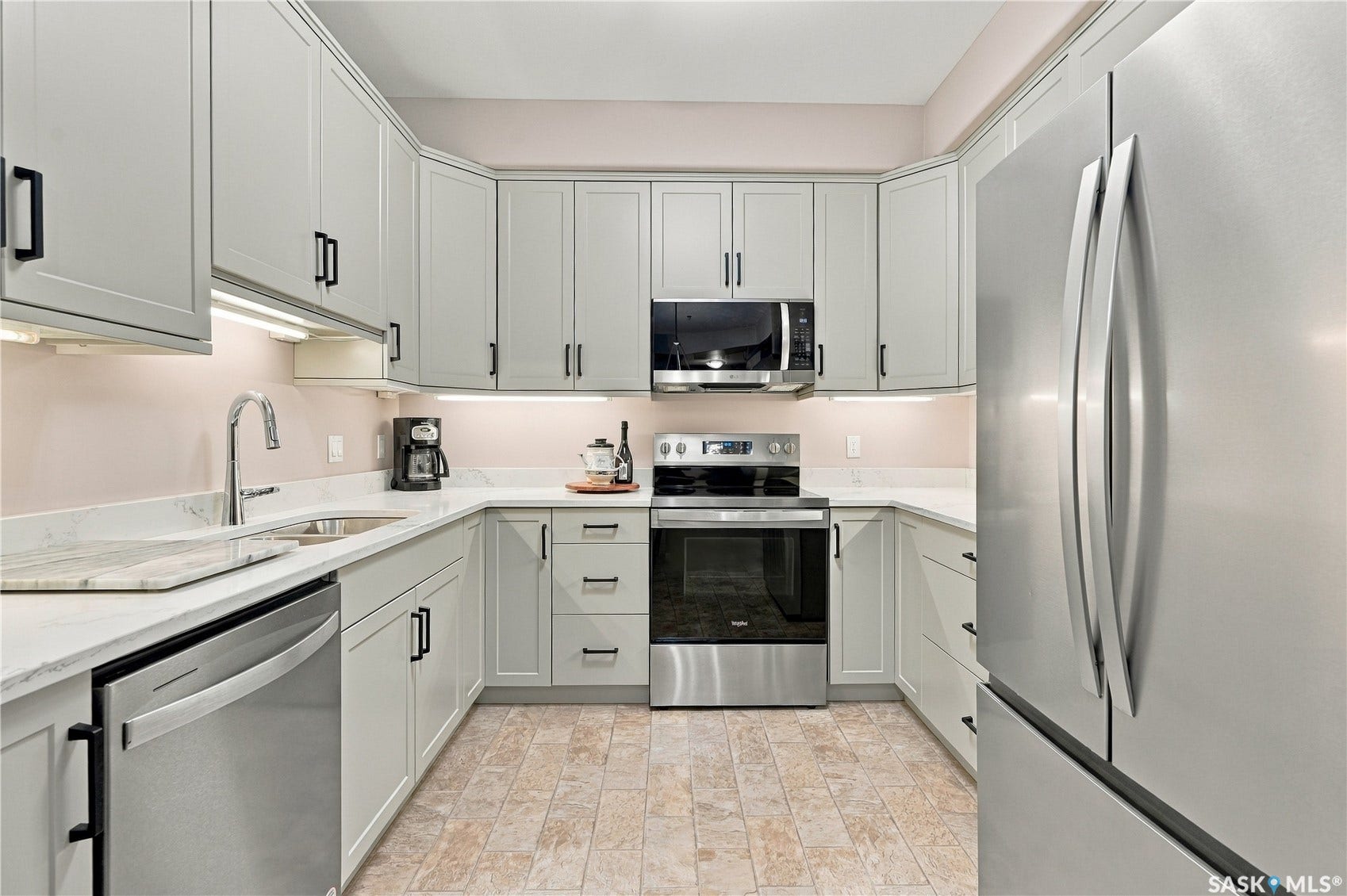 U-shaped kitchen featuring light gray cabinetry, stainless steel appliances, white countertops, and under-cabinet lighting