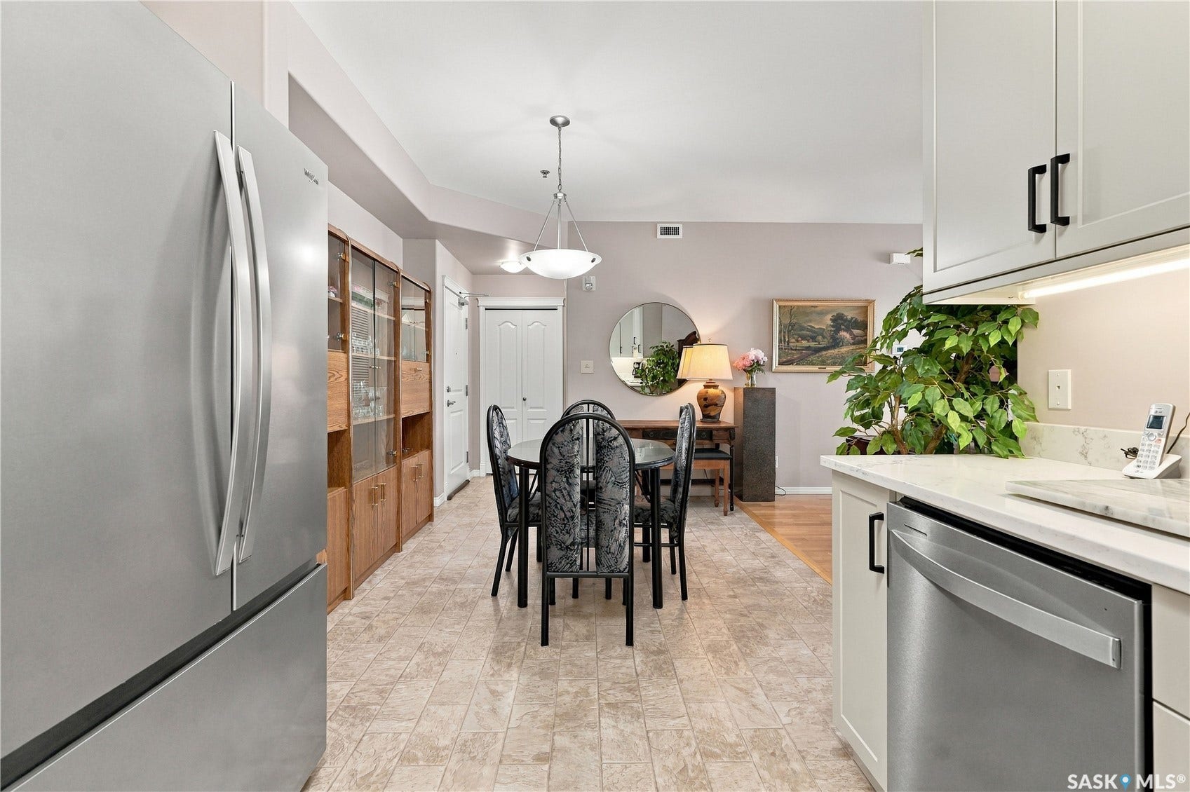 Stainless steel appliances, built-in shelving, white cabinetry, tile flooring, and wood-finish flooring
