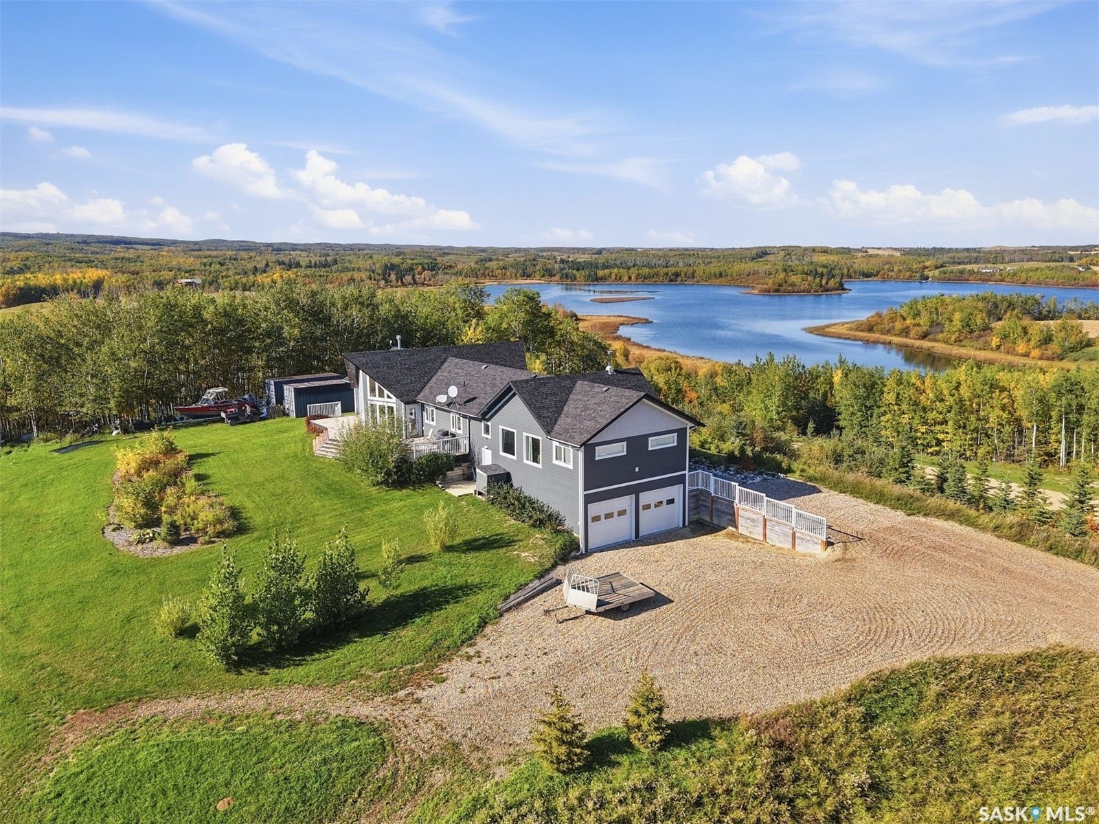 Two-story residence with a two-car garage, expansive green lawn, and a multi-level rear deck