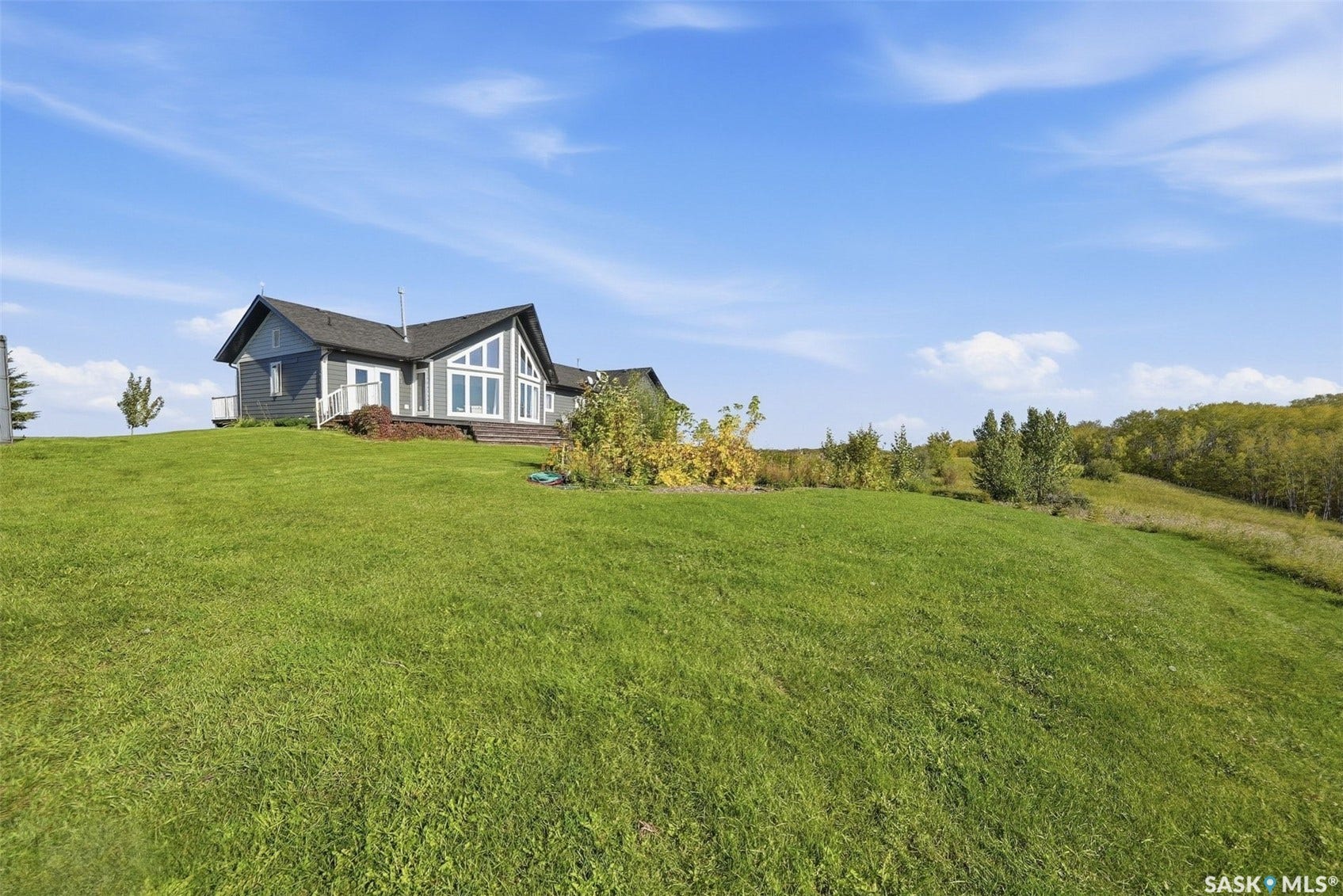Contemporary residence with a dark shingle roof, light gray siding, a prominent A-frame window design, and an elevated deck with white railing