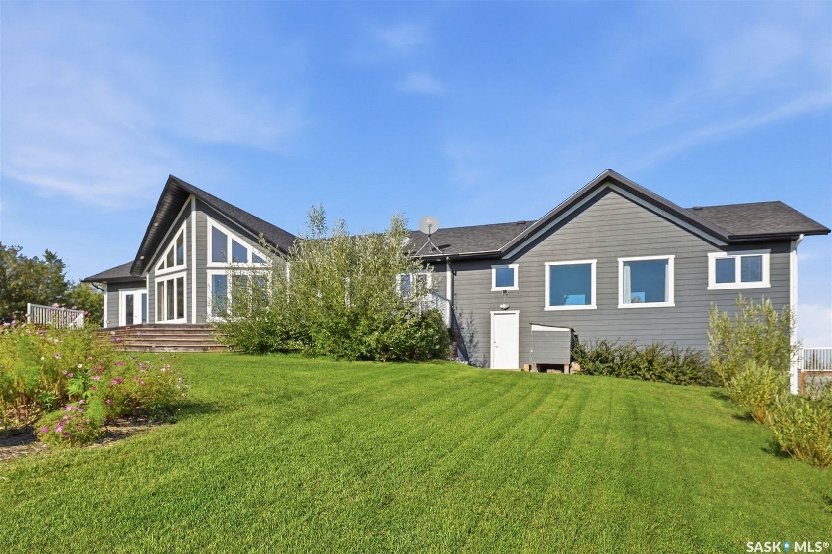 Contemporary exterior with an A-frame window design, grey siding, and a sloped lawn
