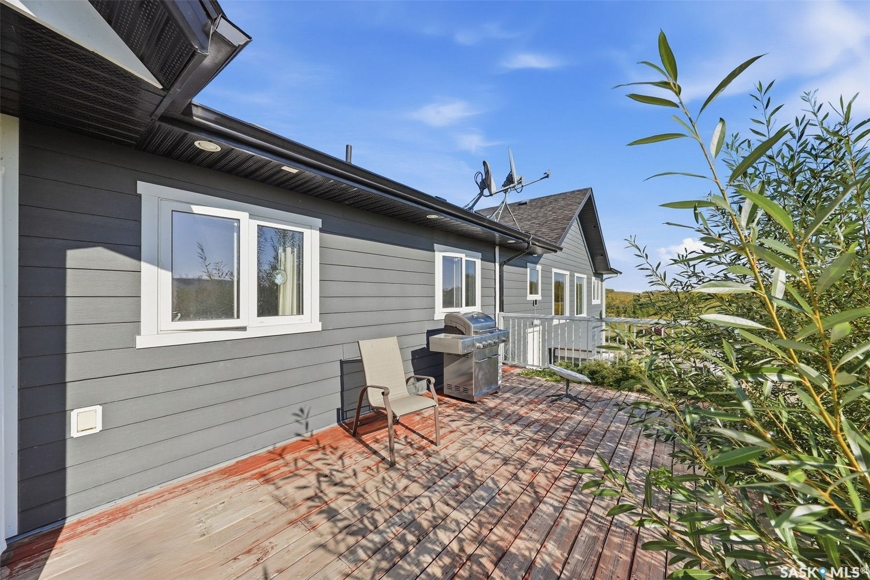 Dark gray horizontal siding with white trim windows and a dark wood-finish deck