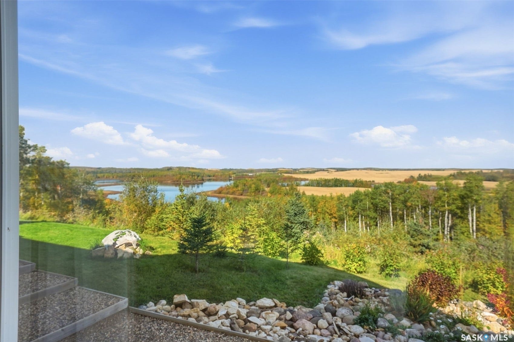 Expansive natural scenery with a lake, distant fields, and varied trees