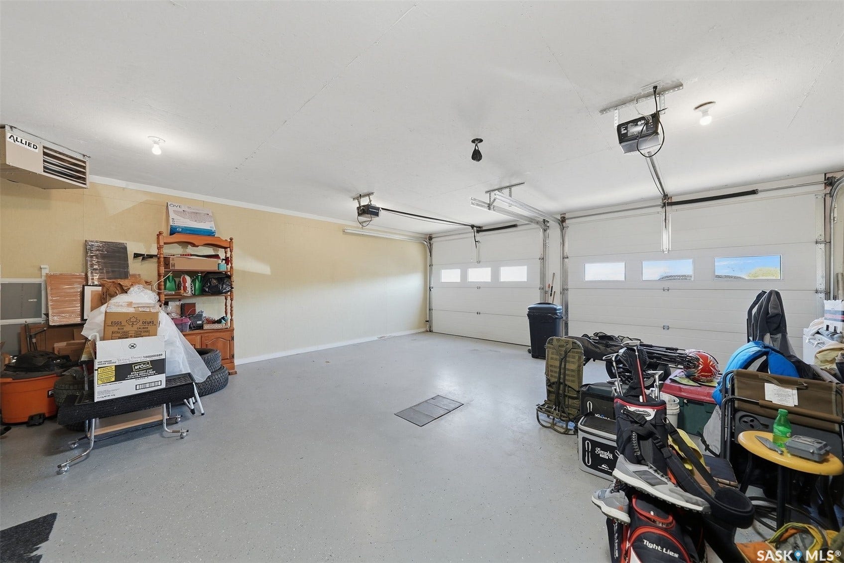 Two garage bays with automatic door openers, overhead lighting, and an attached wall heater