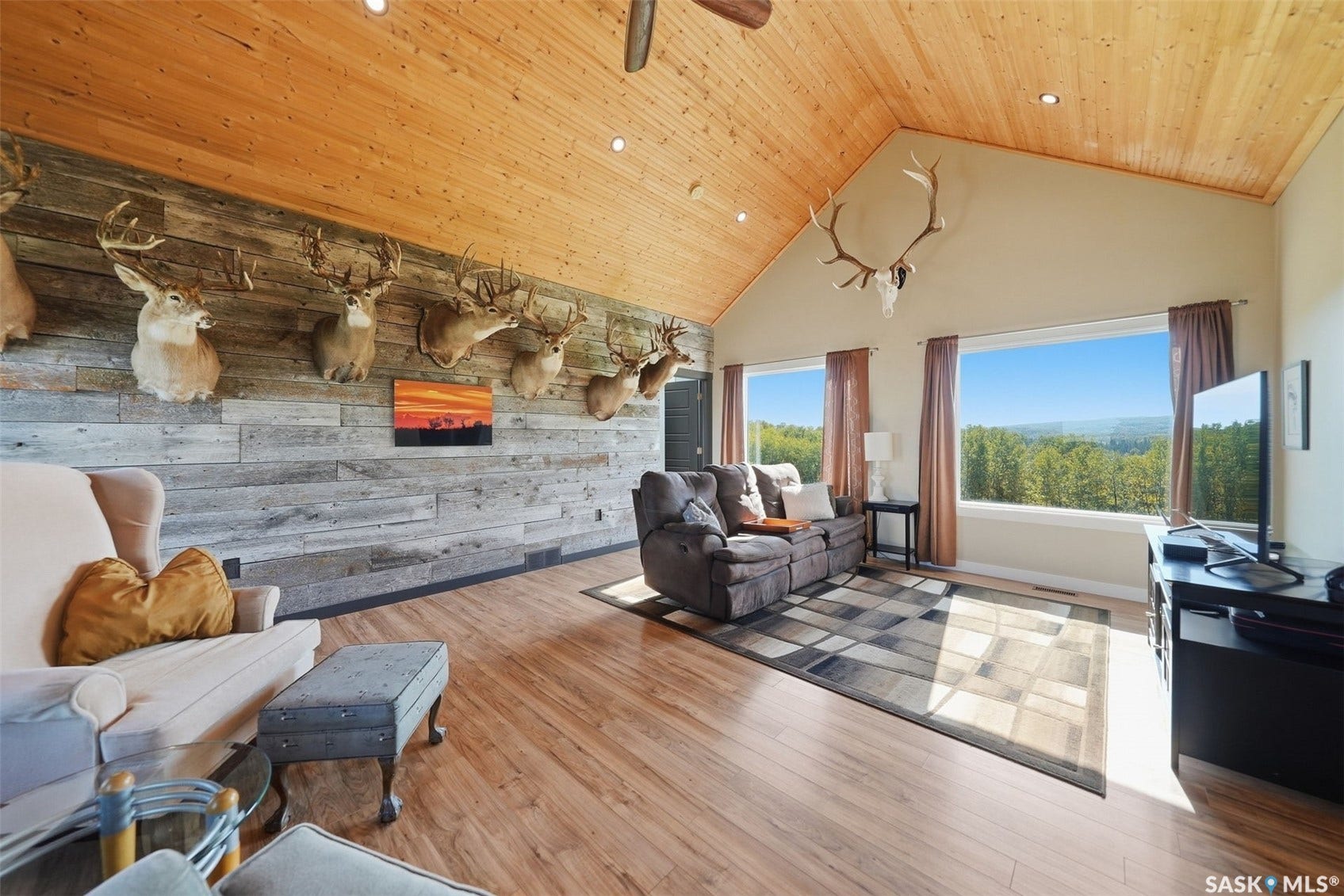Vaulted wood-paneled ceiling, wood-finish flooring, accent wall with horizontal wood planks, expansive windows, recessed lighting