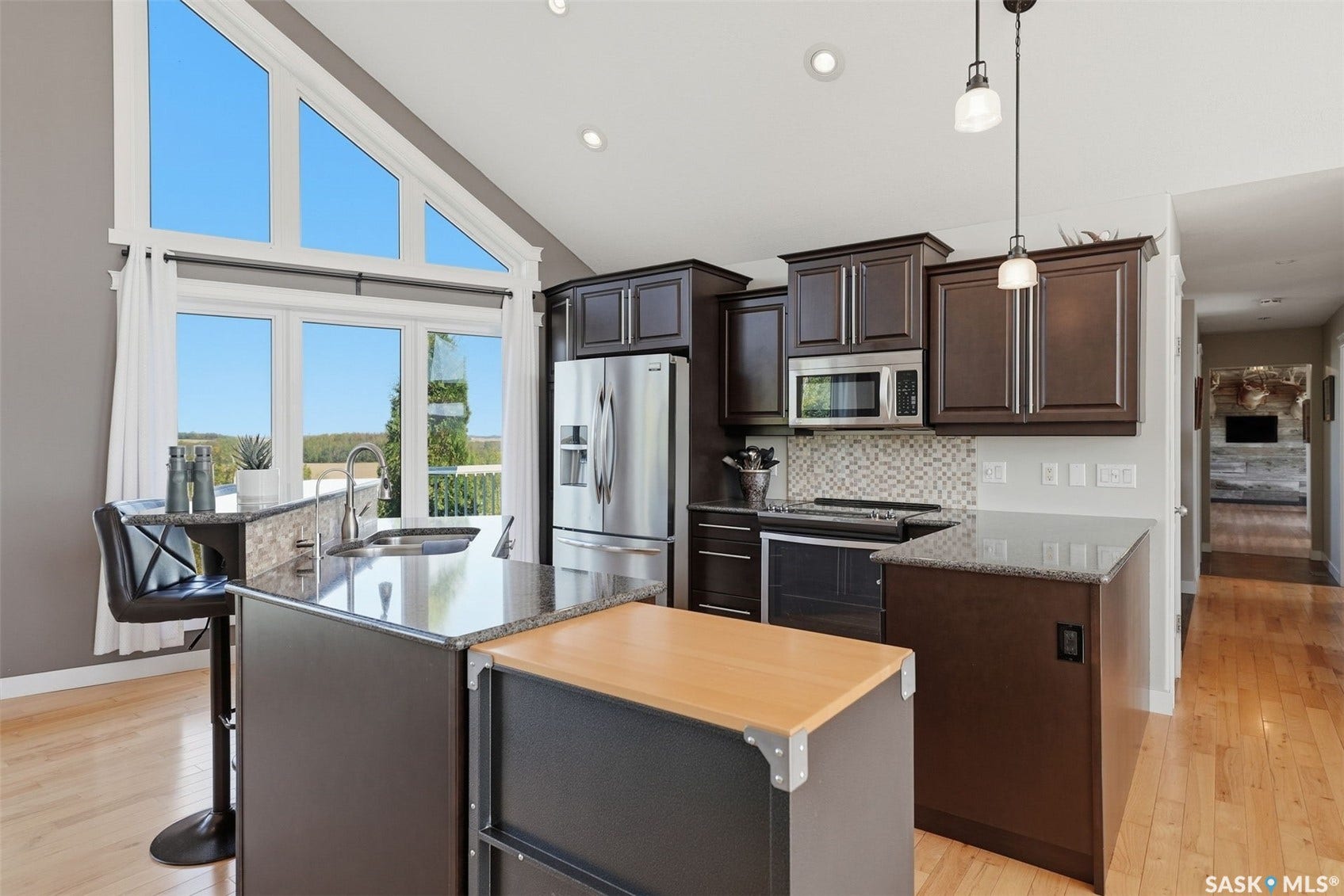 Kitchen featuring dark wood-finish cabinetry, stainless steel appliances, granite countertops, and a full tile backsplash
