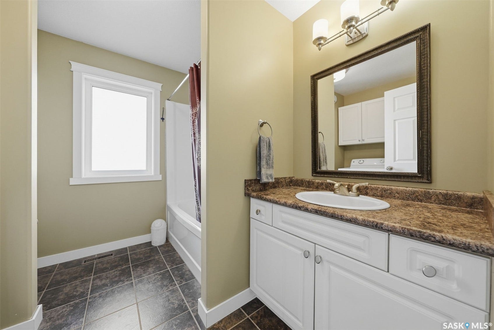 Bathroom featuring a single vanity with white cabinetry, a countertop, an undermount sink, and a framed mirror