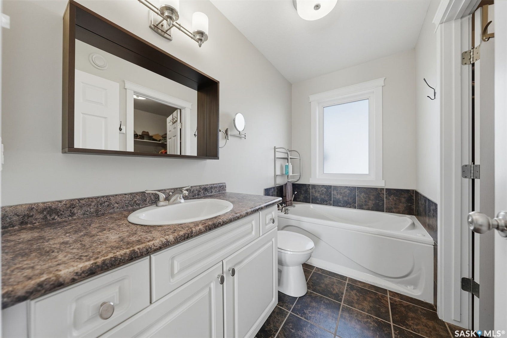 White vanity with round knob pulls, composite countertop, and an undermount sink