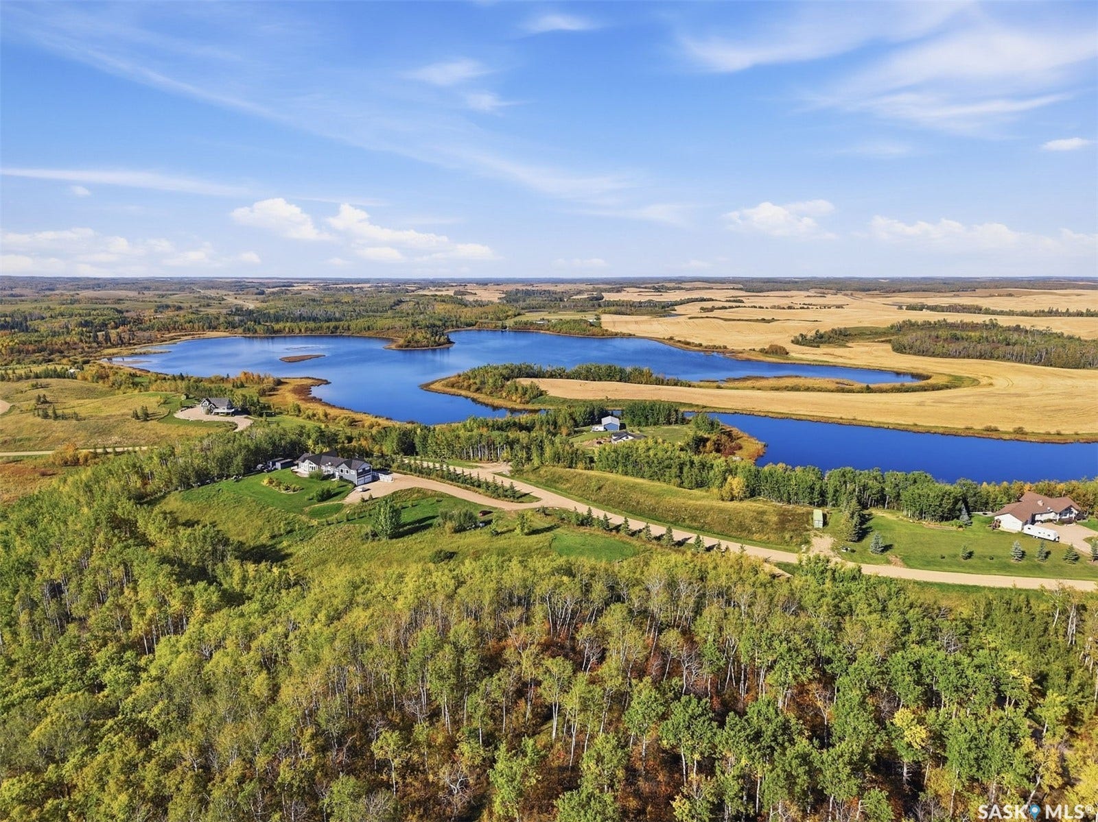 Expansive rural landscape featuring a large body of water, surrounding fields, and forested areas