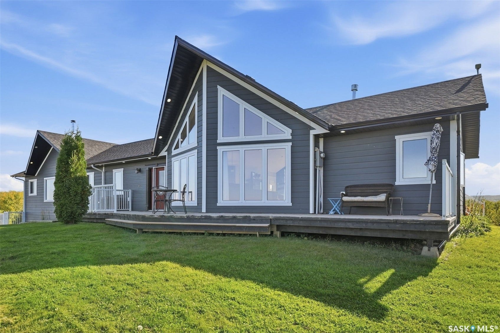 Exterior featuring dark gray horizontal siding, an expansive outdoor deck, and a prominent gable roofline with large windows