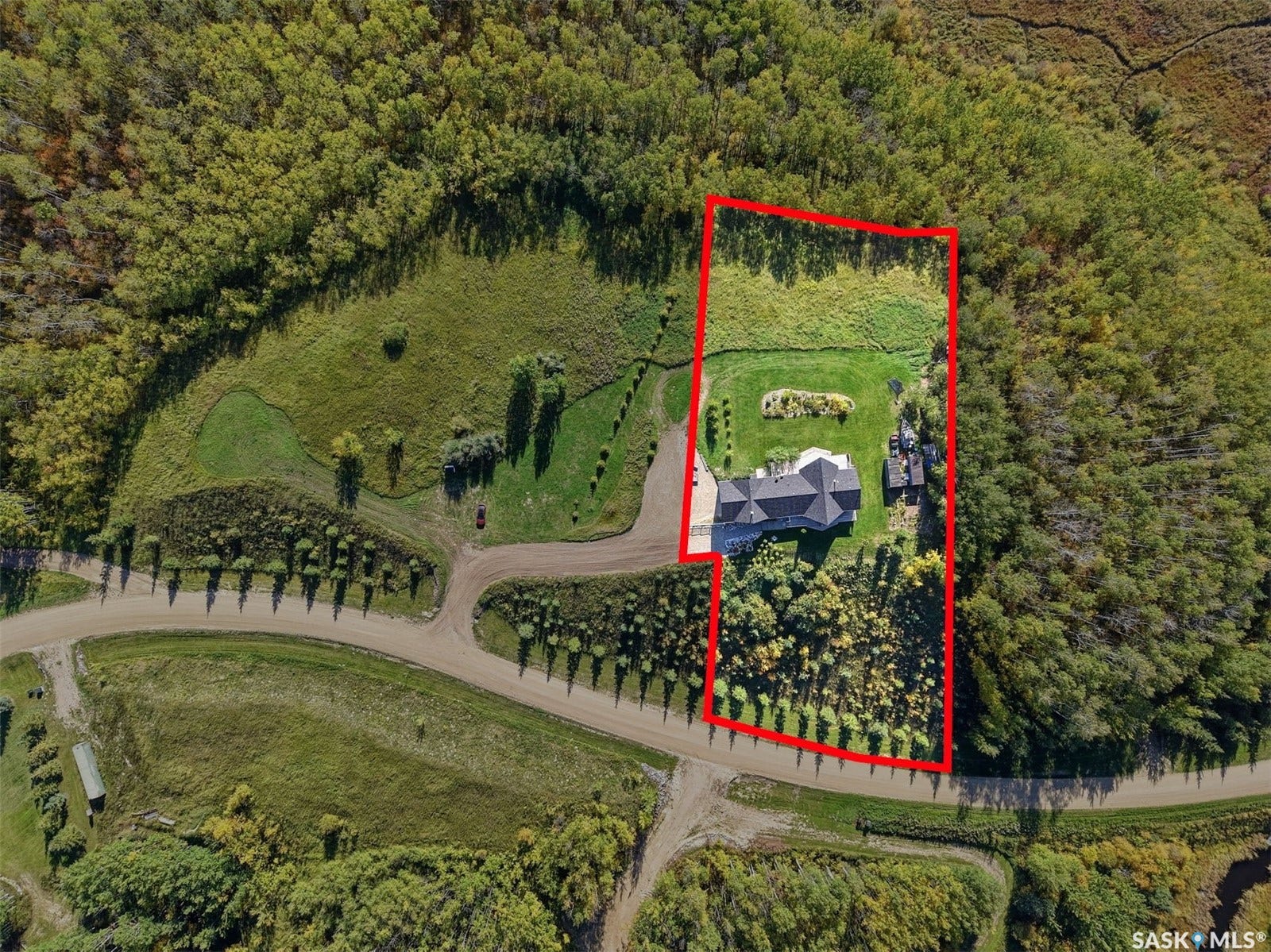 Expansive property featuring a large residence, surrounding green space, mature trees, and a paved driveway