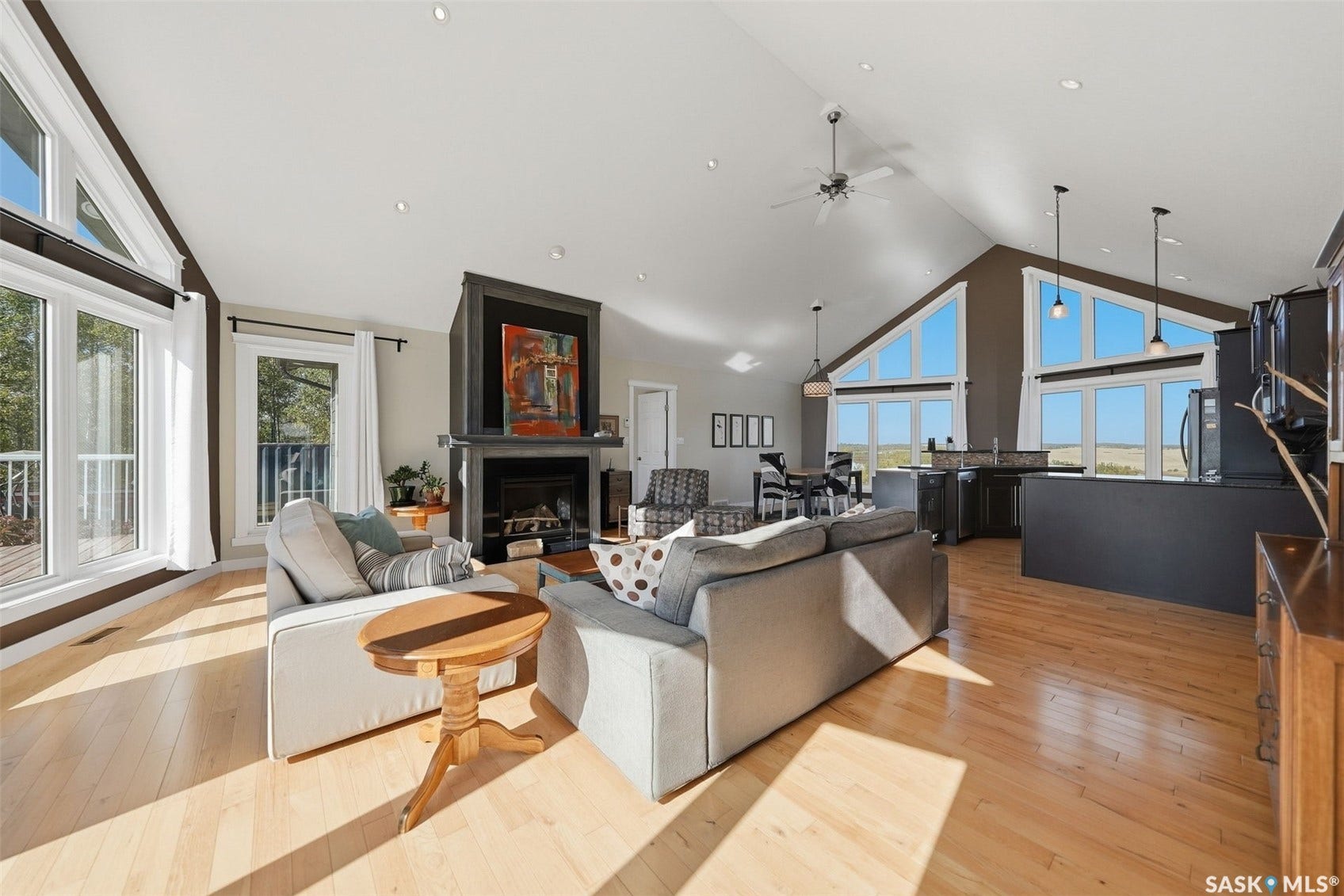 Vaulted ceiling great room with wood-finish flooring, a central fireplace, and recessed lighting