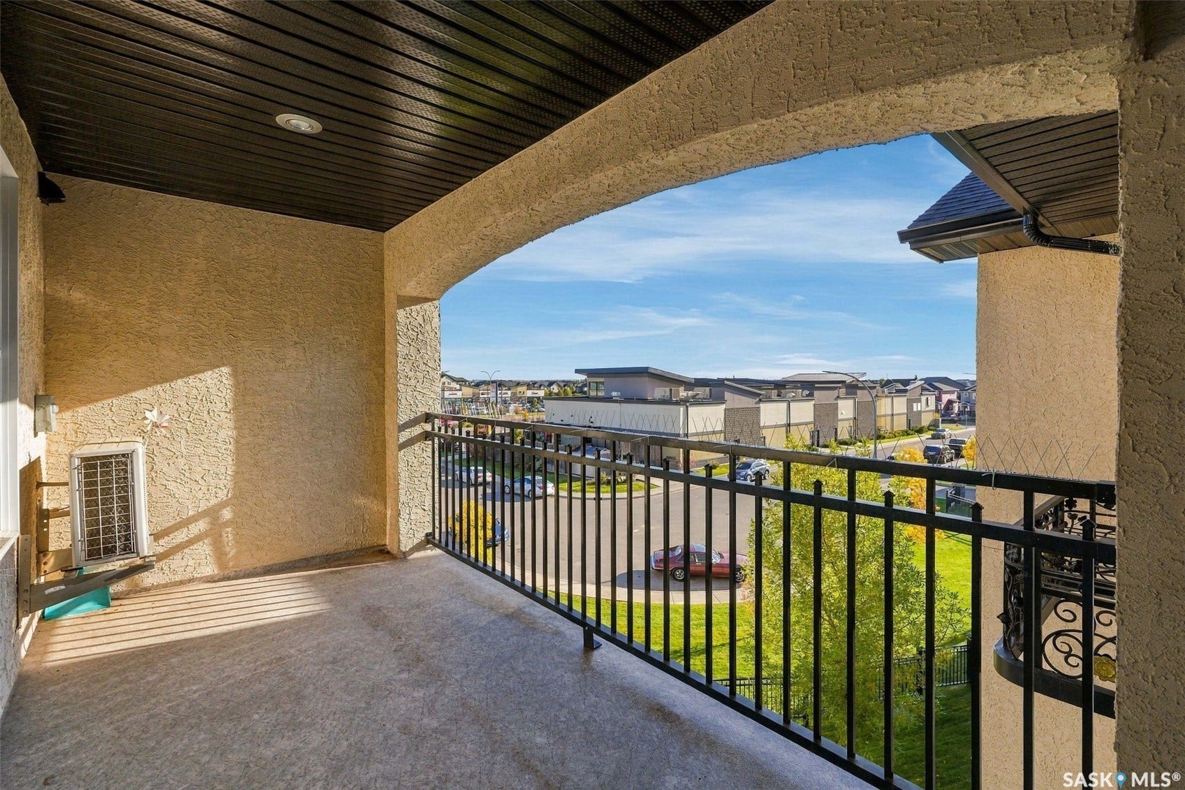 Balcony featuring textured stucco walls, dark soffit ceiling, recessed lighting, and a black wrought iron railing