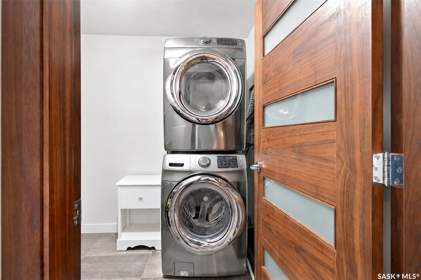 Stackable washer and dryer appliances, wood-finish doors with frosted glass panels, and tile flooring