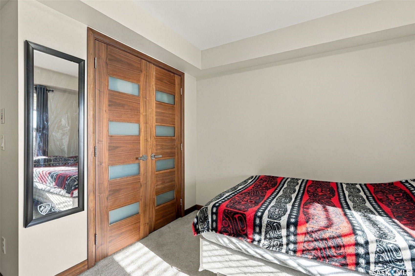 Light-toned wall paint, warm wood-finish bi-fold doors with frosted glass panels, and a neutral-toned carpet