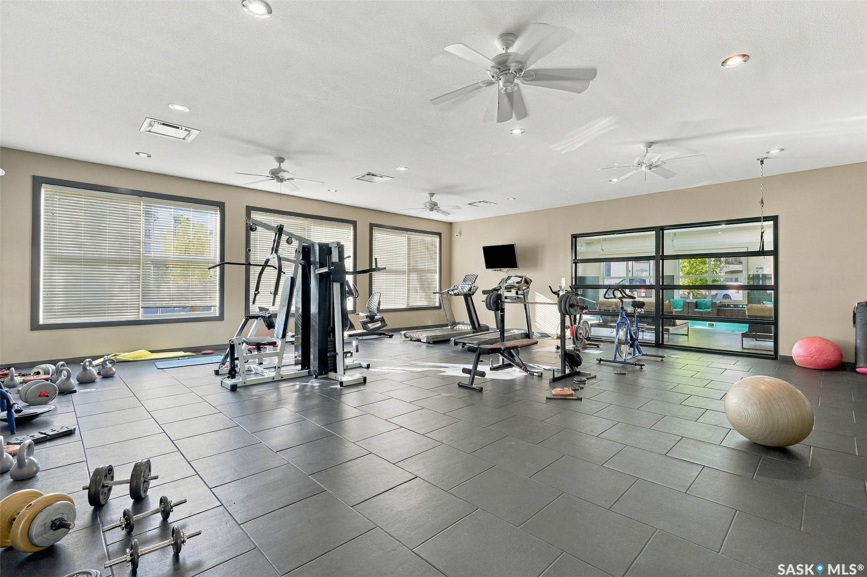 Spacious room featuring multiple ceiling fans, recessed lighting, and large windows with blinds