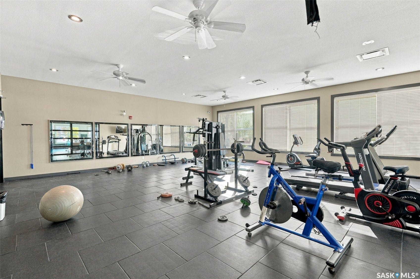 Fitness room featuring a tiled floor, multiple ceiling fans, recessed lighting, and mirrored walls