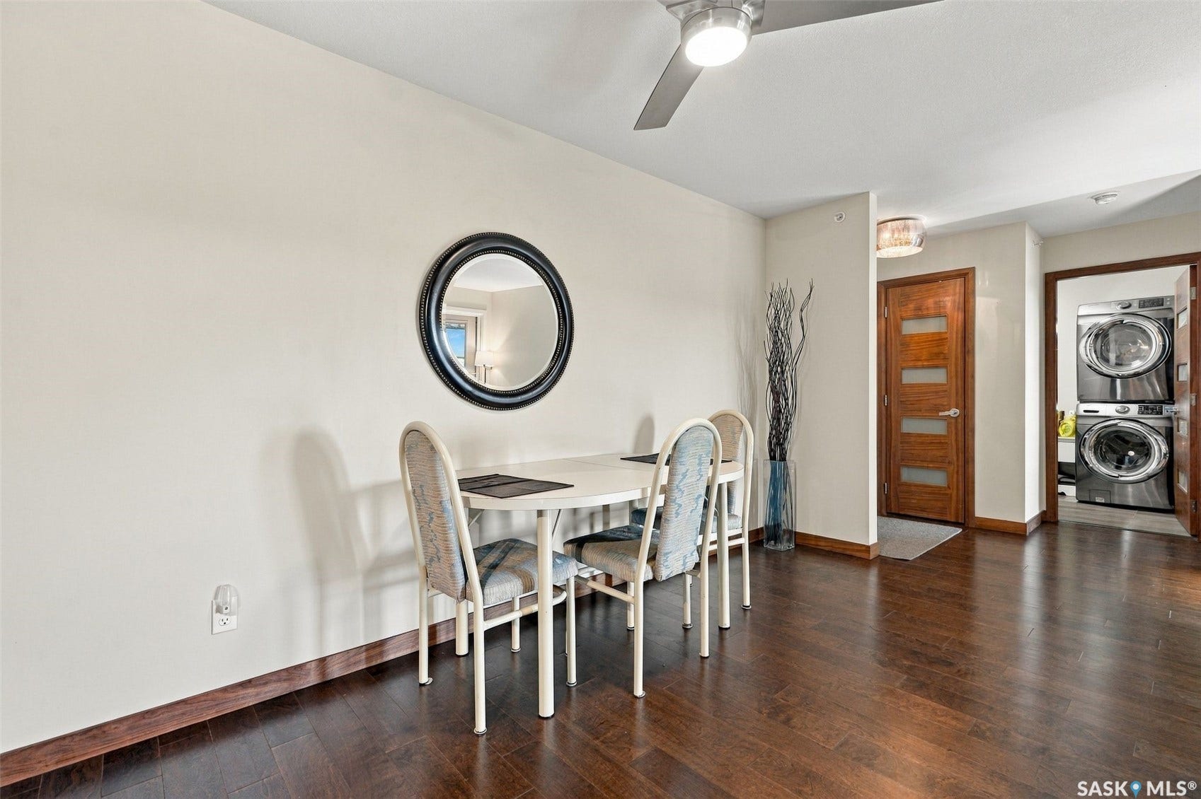 Dark wood-finish flooring throughout, light-toned walls, and a ceiling fan with integrated lighting