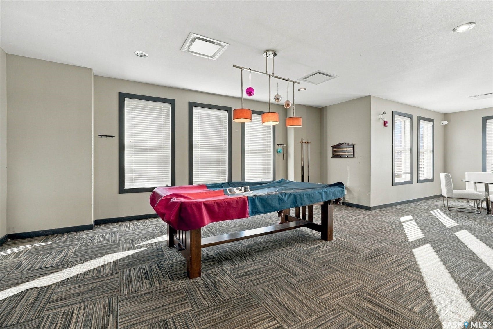 Recessed lighting, contemporary pendant lighting, multiple windows with blinds, and patterned carpeting