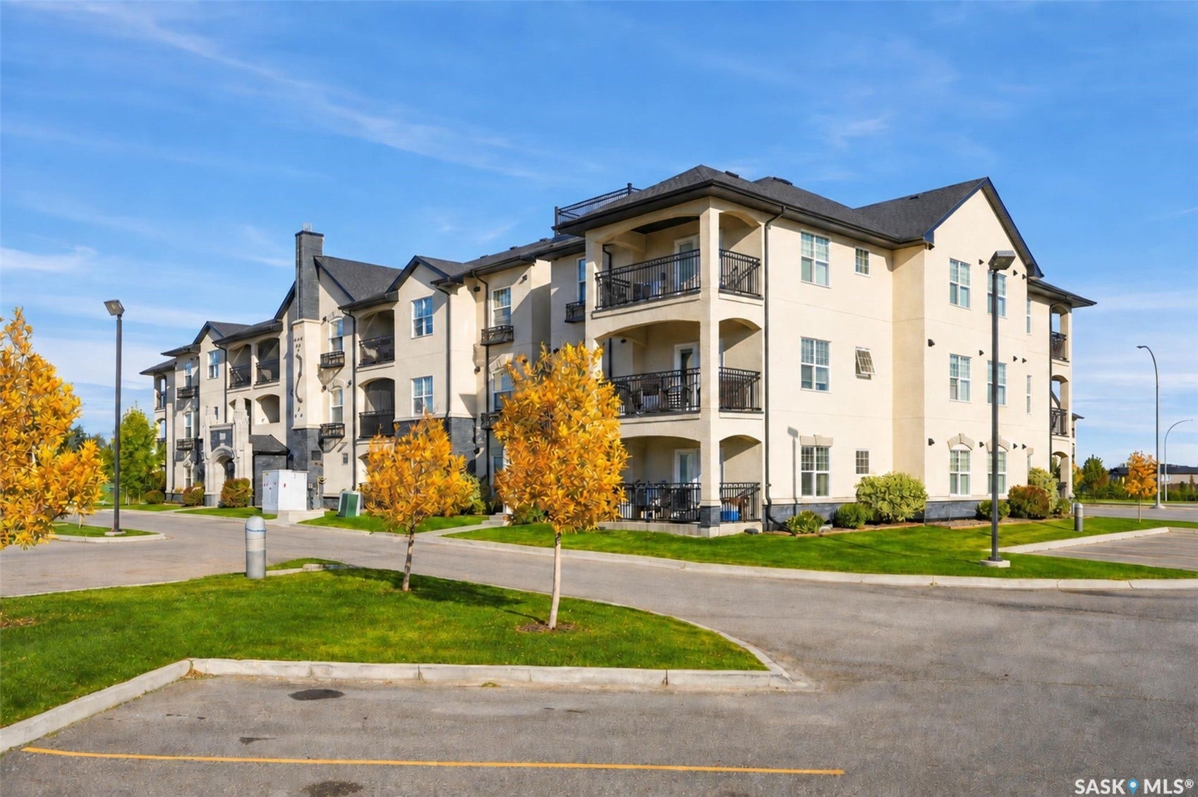 Multi-story building featuring light-colored exterior siding, dark-toned roofing, and multiple balconies with dark railings