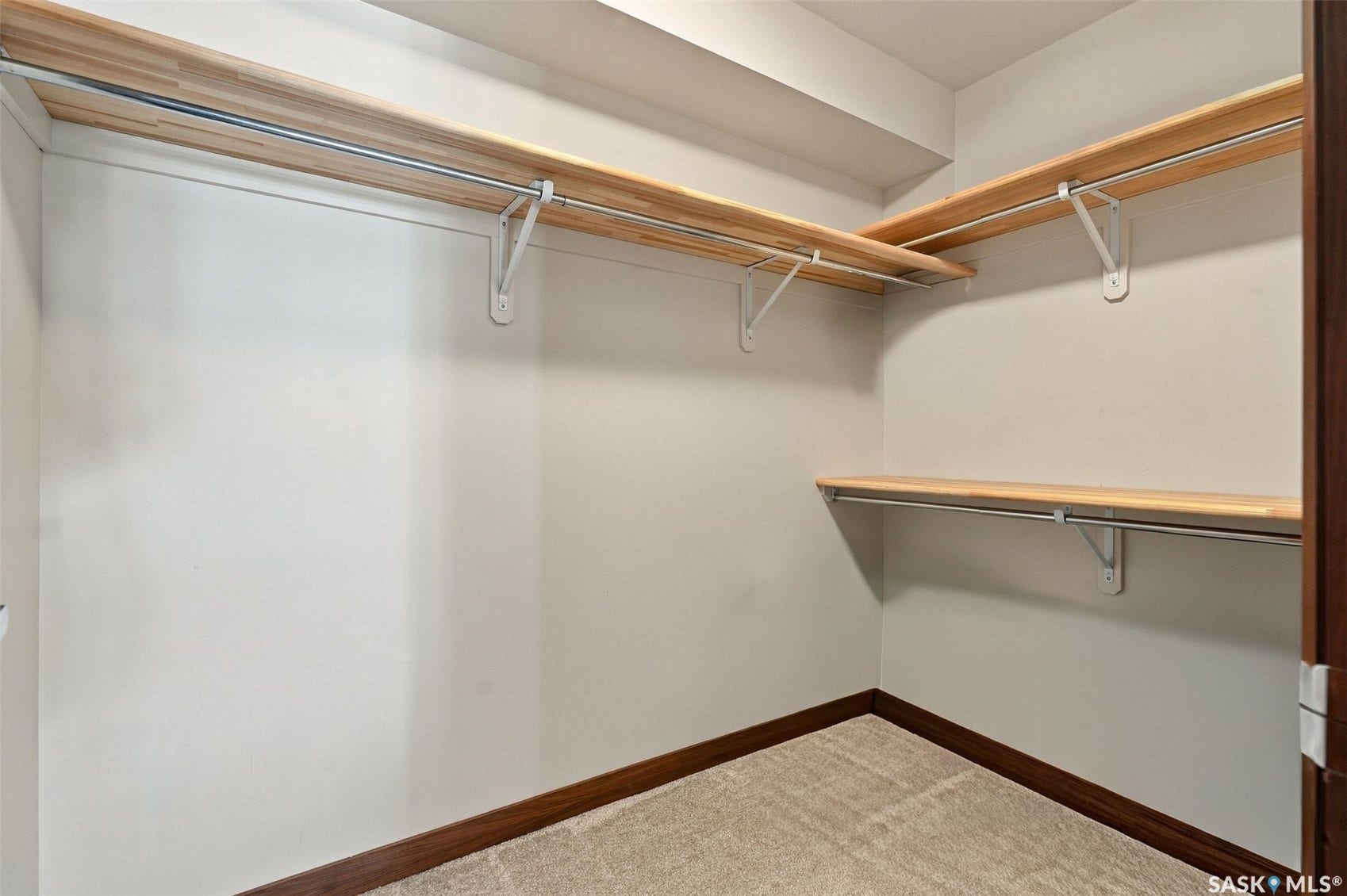 Expansive walk-in closet with multiple wood-finish shelves and metal hanging rods