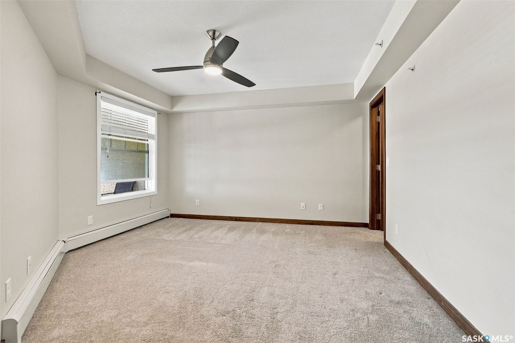 Carpeted room featuring a ceiling fan with integrated lighting, a window with horizontal blinds, and a wood-finish door