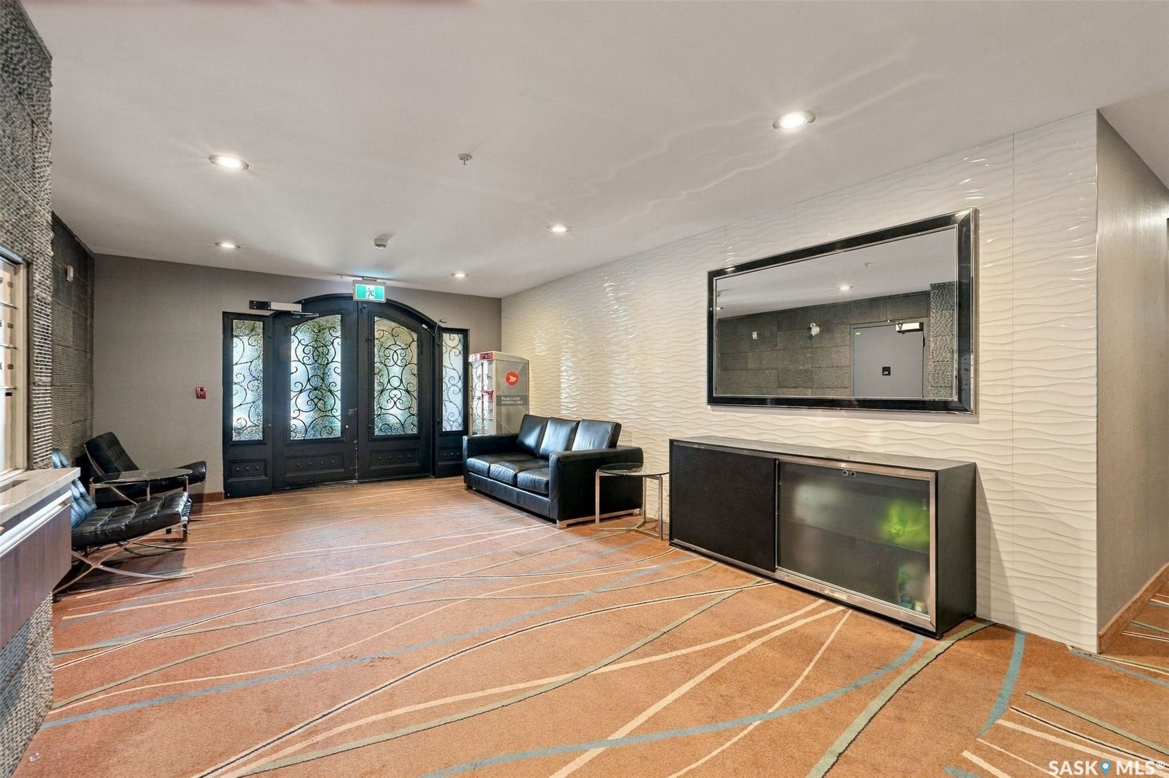 Arched double entry doors with decorative glass panels, patterned flooring, textured wall paneling, and recessed lighting