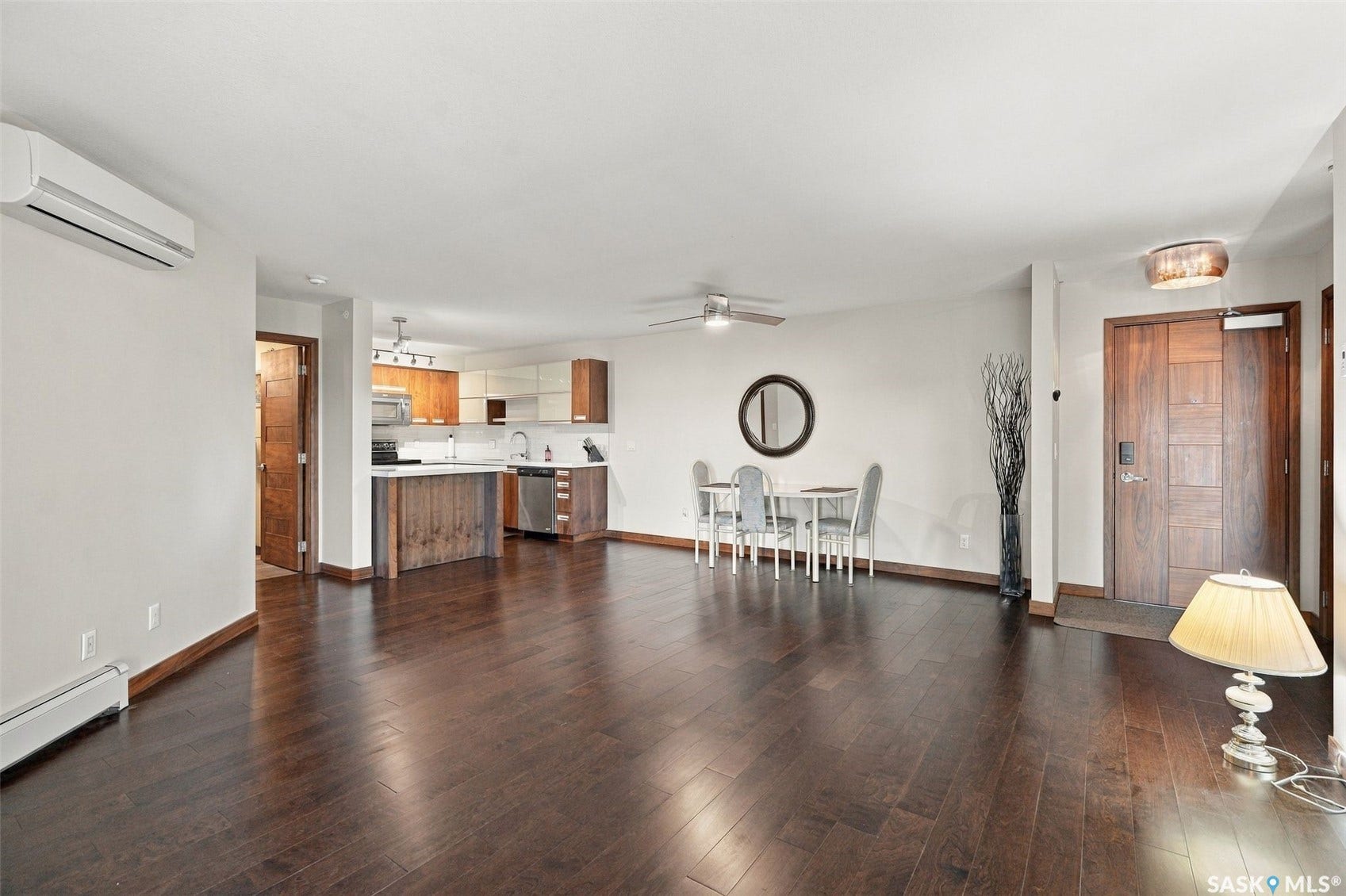 Dark wood-finish flooring throughout, kitchen with stainless steel appliances, white countertops, and wood cabinetry