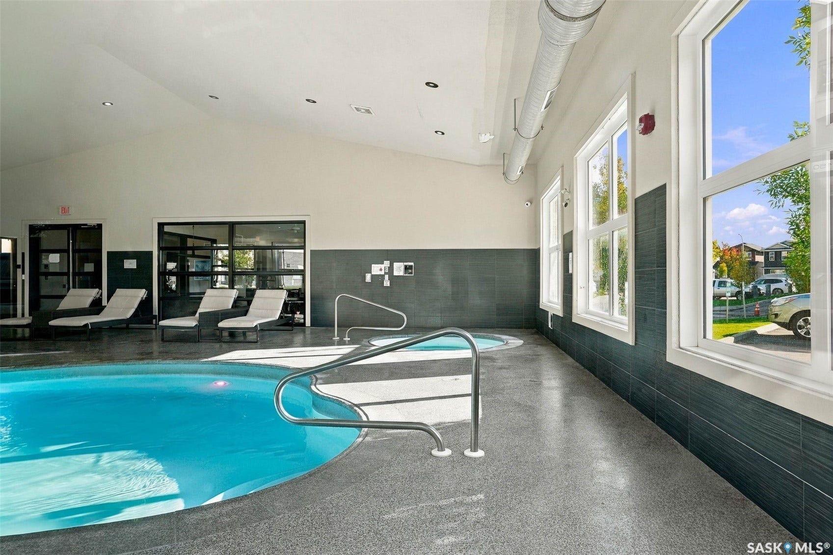 Indoor aquatic area featuring a swimming pool, integrated spa, and large windows