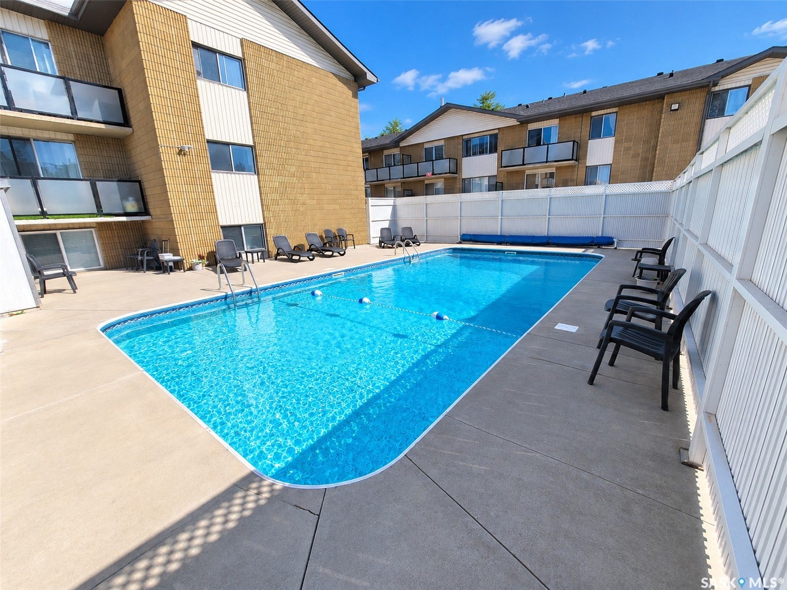Outdoor swimming pool with concrete decking and white privacy fencing
