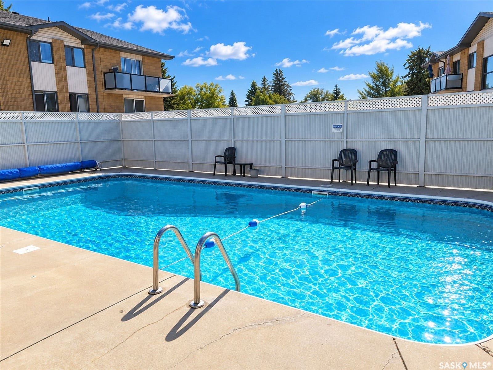 In-ground swimming pool with concrete surround and metal access rails