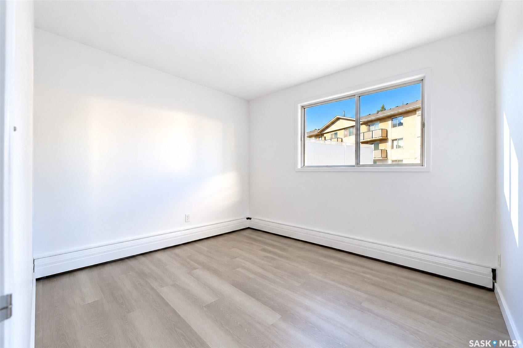 Light wood-finish flooring, white walls, and a large window with white trim