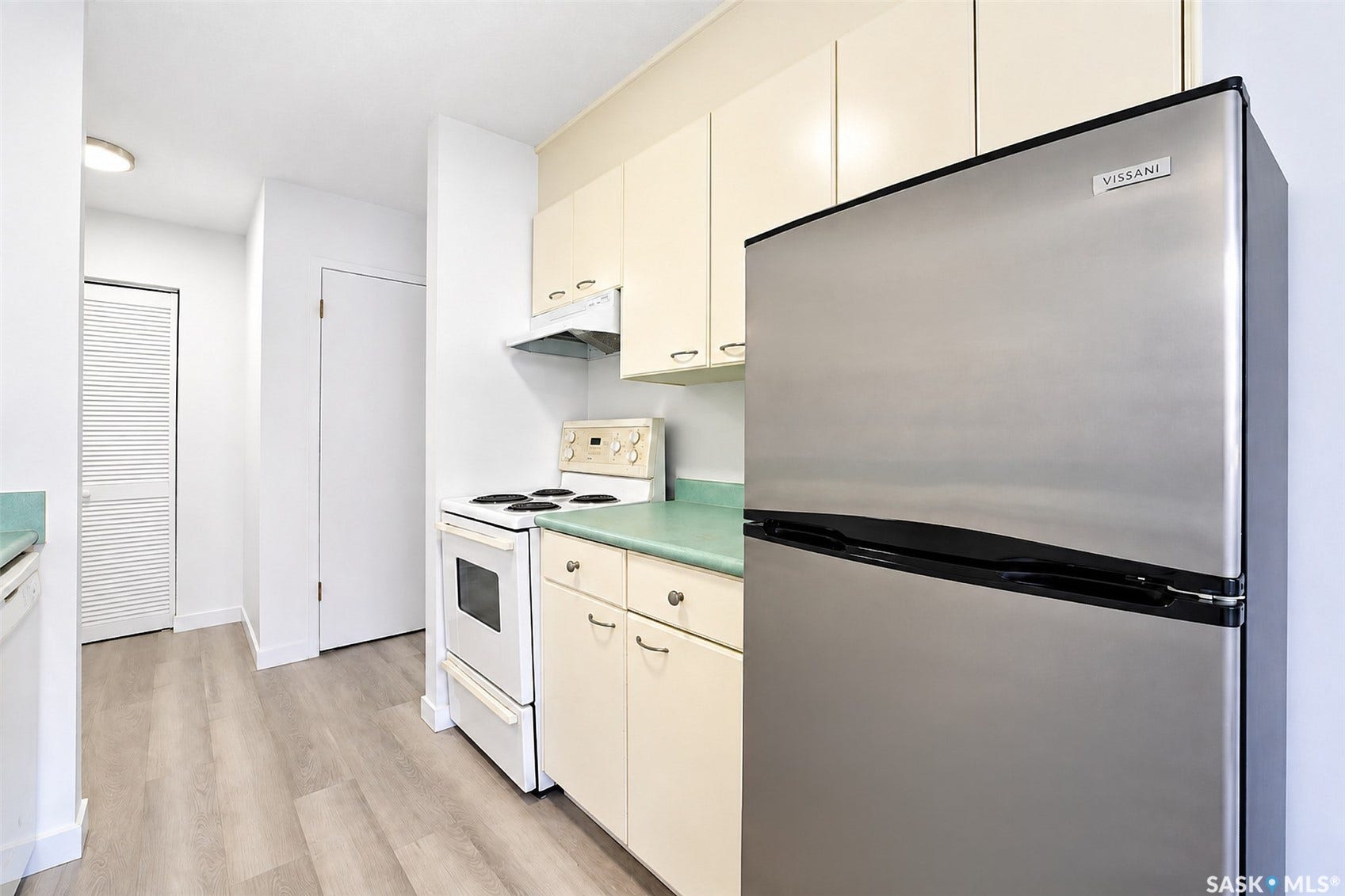 Kitchen featuring light wood-finish flooring, white appliances, and a stainless steel refrigerator