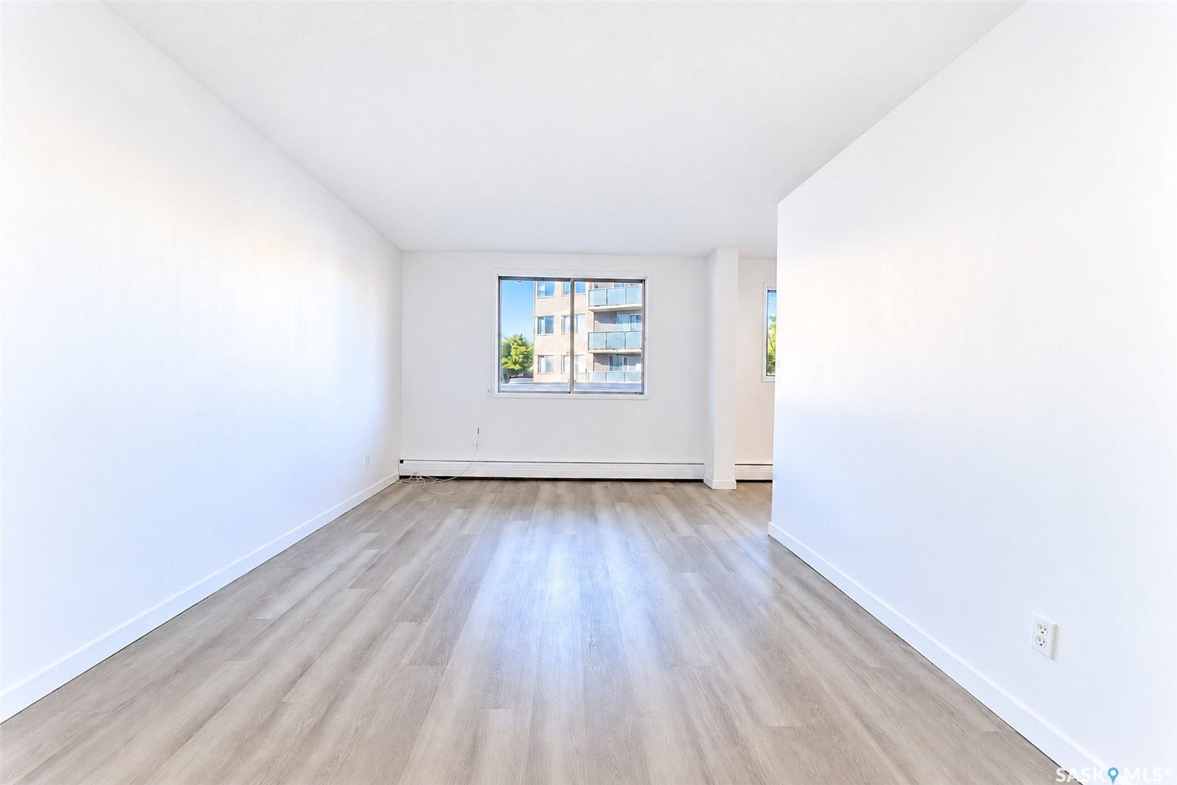 Wood-finish flooring, white walls, and a window providing natural illumination