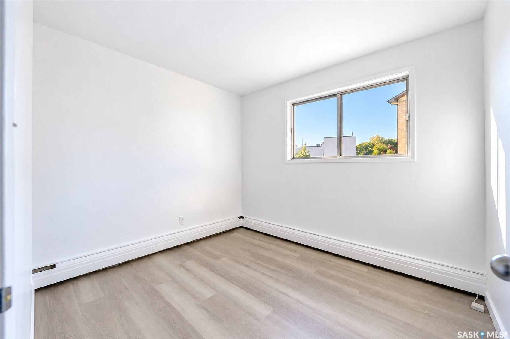 White walls, wood-finish flooring, and a large window
