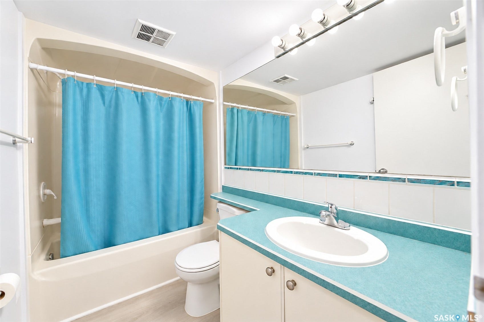 Full-sized bathtub with shower, toilet, and vanity featuring an integrated sink, laminate countertop, and lower cabinetry