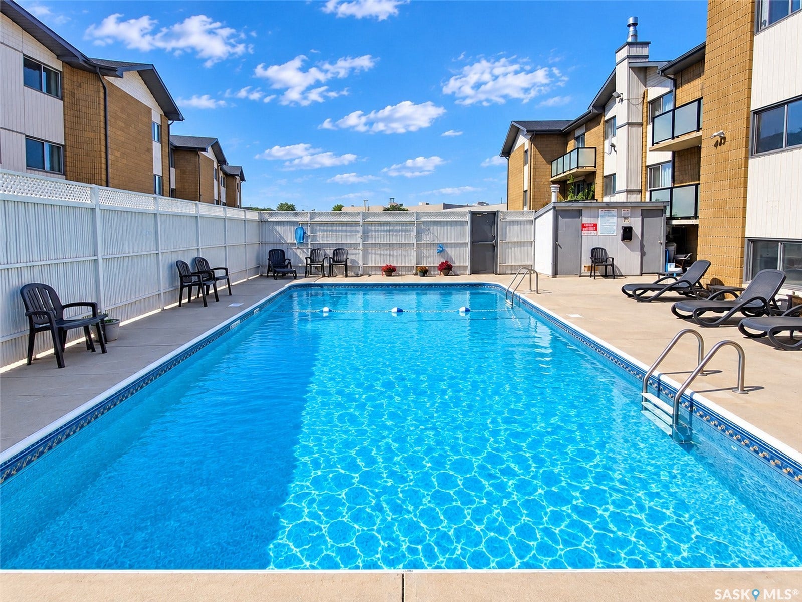 Outdoor swimming pool with concrete surround and white lattice fencing