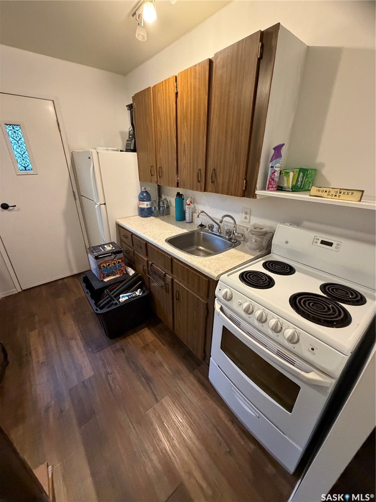 301 2nd Street, #1-10, Kennedy SK S0G 2R0 Kitchenette featuring wood-finish flooring, wood cabinetry, a built-in stainless steel sink, a white freestanding range, and a white refrigerator