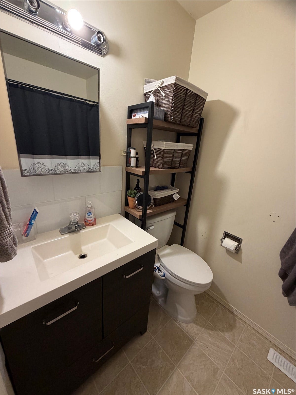 301 2nd Street, #1-10, Kennedy SK S0G 2R0 Bathroom featuring a single vanity with a white countertop and dark wood-finish cabinetry, a rectangular wall-mounted mirror, and a toilet