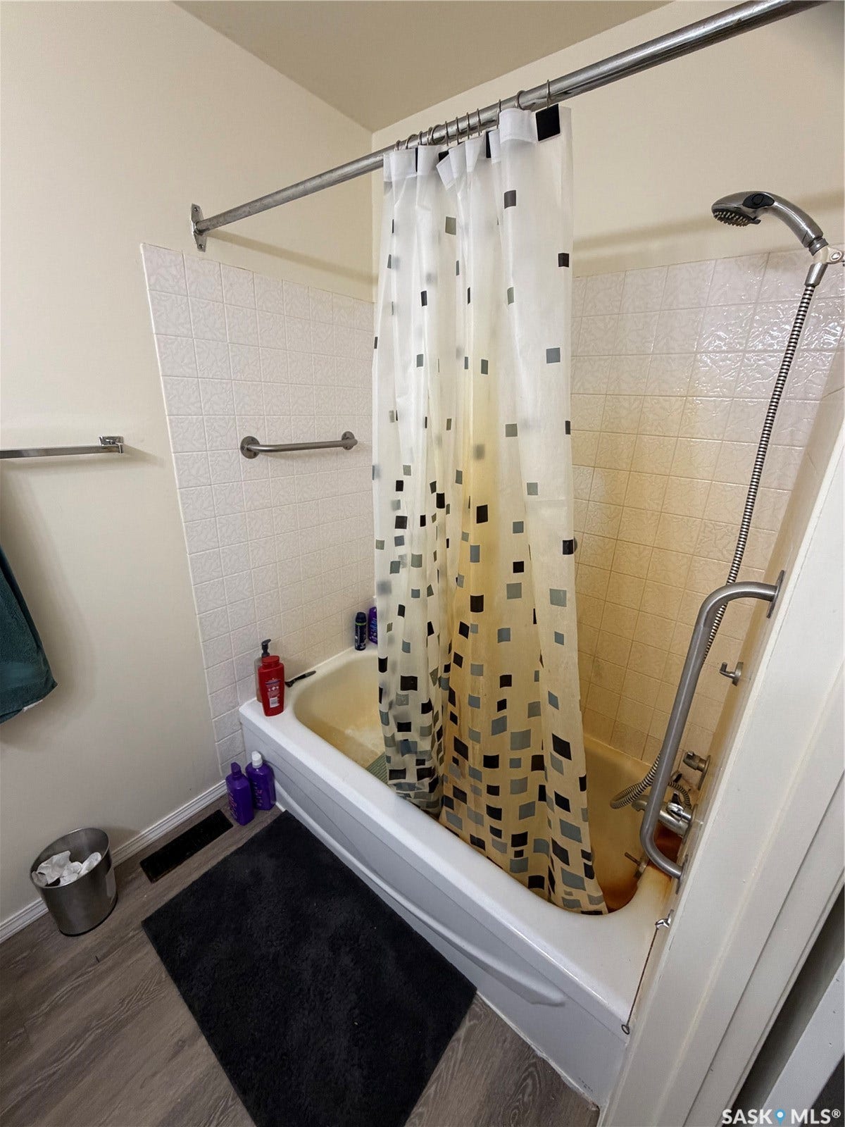 301 2nd Street, #1-10, Kennedy SK S0G 2R0 White bathtub with a textured tile surround, chrome shower rod, and wood-finish flooring