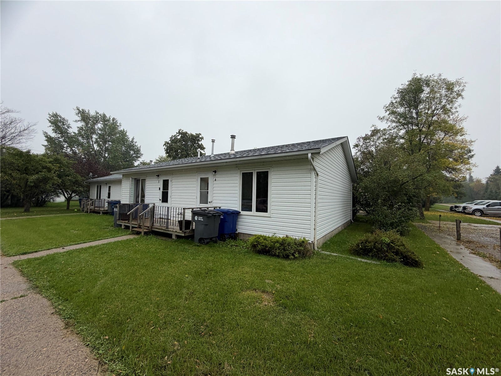301 2nd Street, #1-10, Kennedy SK S0G 2R0 White vinyl siding exterior with multiple entry doors, each featuring a wood deck and handrail