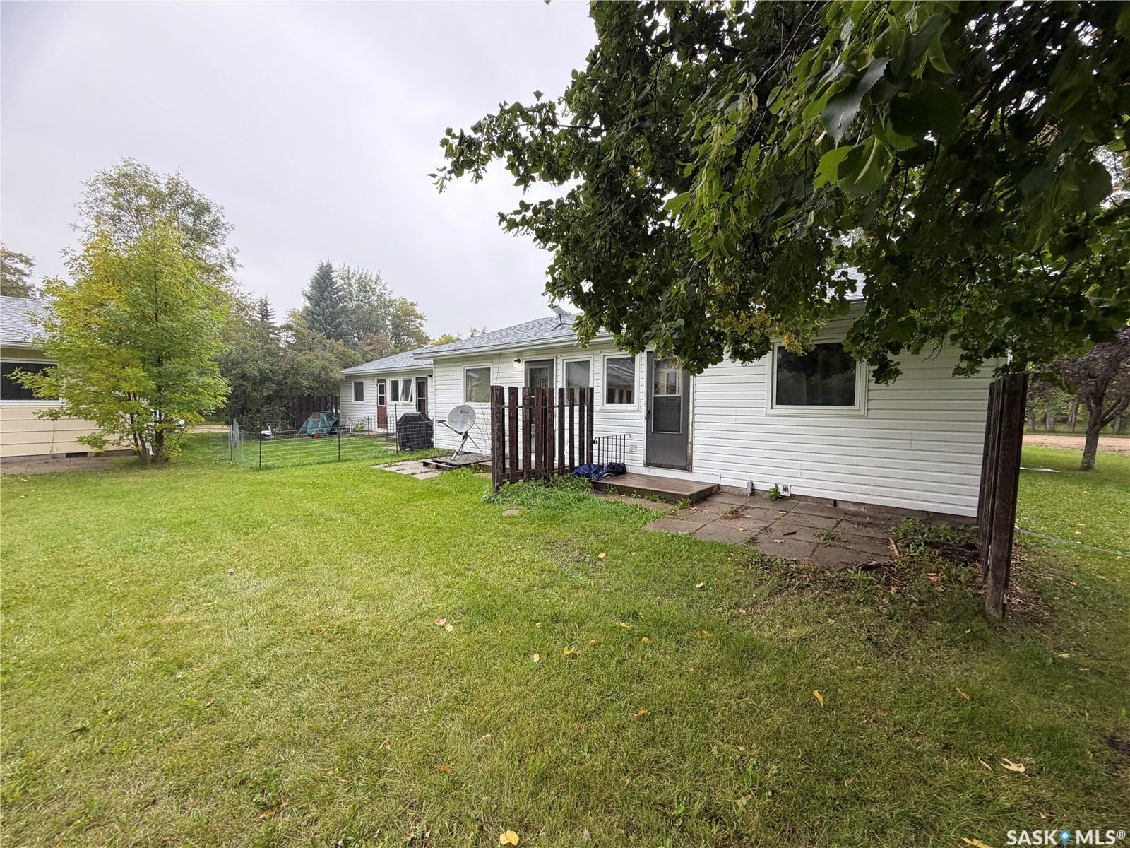 301 2nd Street, #1-10, Kennedy SK S0G 2R0 Expansive green lawn with mature trees and a paved patio area